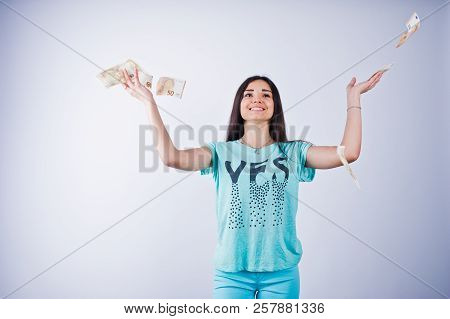 Portrait Of An Attractive Girl In Blue Or Turquoise T-shirt And Trousers Throwing A Lot Of Money.