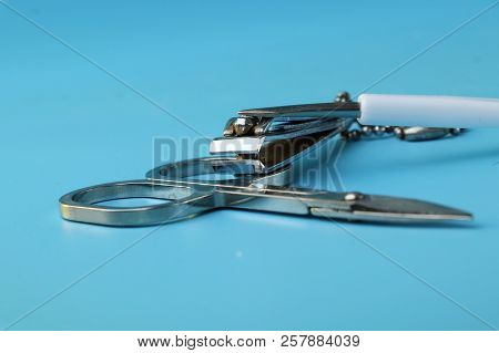 A Manicure Scissors With Small Nail File On Blue Background. Casual Things For Women