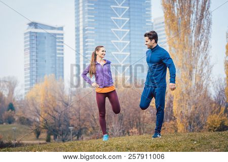 Sport couple doing warm-up exercise before starting a run to become more fit