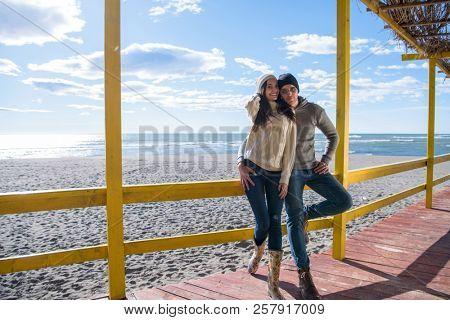 Happy couple enyojing time together on beach during autumn day