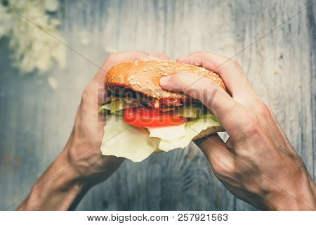 Man Eats A Big Sandwich With Meat And Wegetables