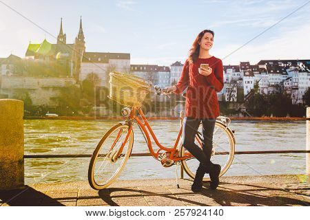 Theme Tourism On Bicycle And Modern Technology. Beautiful Young Caucasian Woman Stands Near Red Retr