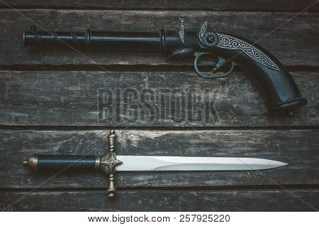 Musket Gun And Dagger Knife On Wooden Table Background With Copy Space.