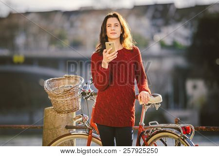 Theme Tourism On Bicycle And Modern Technology. Beautiful Young Caucasian Woman Stands Near Red Retr