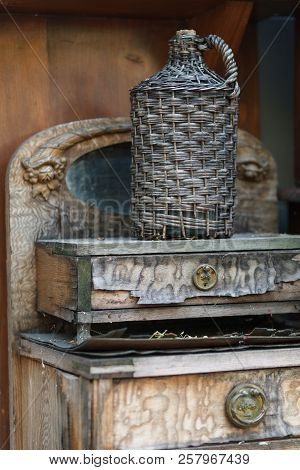 Carboy In Wicker Basket On Wooden Table