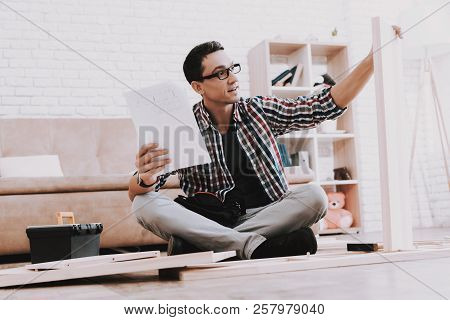 Young Man Assembling Wooden Bookshelf At Home. Wooden Bookcase. Selfmade Furniture. Man And Hobby. W