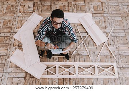 Young Man Assembling Wooden Bookshelf At Home. Wooden Bookcase. Selfmade Furniture. Man And Hobby. W