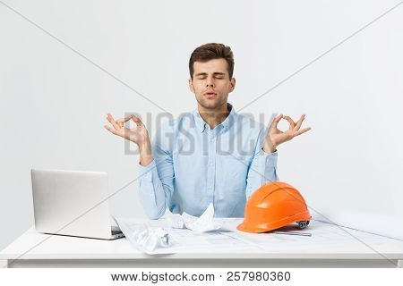 Young Handsome Engineer Or Constructor Man In Blue Suit Practice Yoga And Relax At Office Room.