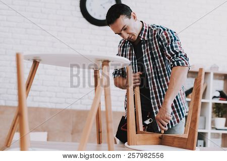 Young Man Assembling Coffee Table And Stools. Furniture Fittings. Engineer With Tool. Young Man At H