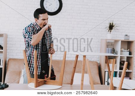 Young Man Assembling Coffee Table And Stools. Furniture Fittings. Engineer With Tool. Young Man At H