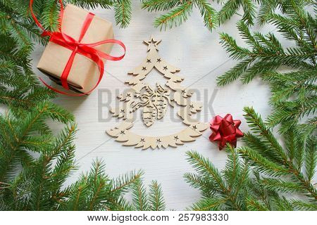 Christmas Background. Green Tree Branches Frame On White Wooden Background, Gift Box With Red Satin 