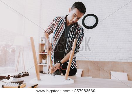 Young Man Assembling Coffee Table And Stools. Furniture Fittings. Engineer With Tool. Young Man At H
