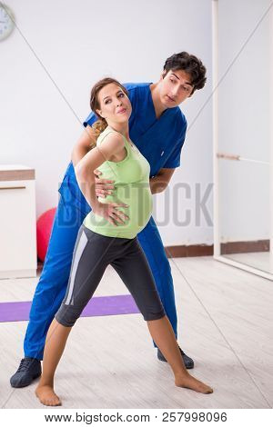 Pregnant woman doing physical exercies with instructor