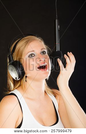 Music, Passion, Stage-fright Concept. Blonde Young Woman Singing To Microphone And Wearing Big Headp