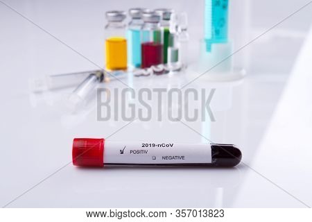 Test Tube With Coronavirus Positive Result. White Reflective Table Surface.