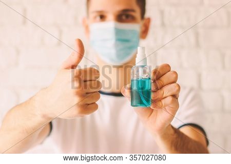 Young Man Showing Like With Thumb Up And Holding Sanitizer Dispenser In Hand. Confident Doctor In Me