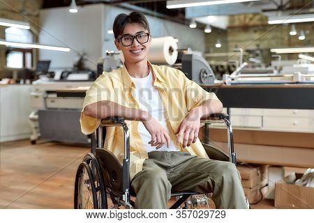 Portrait Of Young Male Office Worker In A Wheelchair Looking At Camera While Posing In Co-working Sp