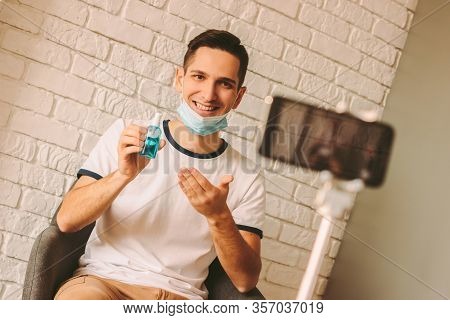 Handsome Blogger Wearing Medical Mask On Face And Recording Video Content On Smart Phone Camera. You