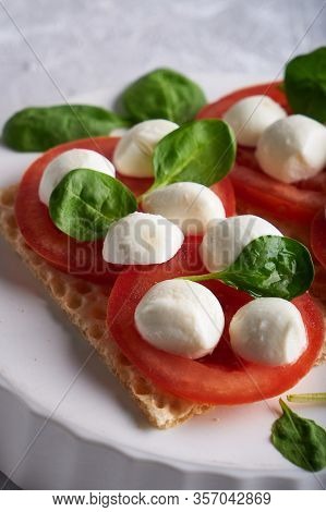 Toasts With Mozzarella, Tomatoes And Spinach In A White Plate
