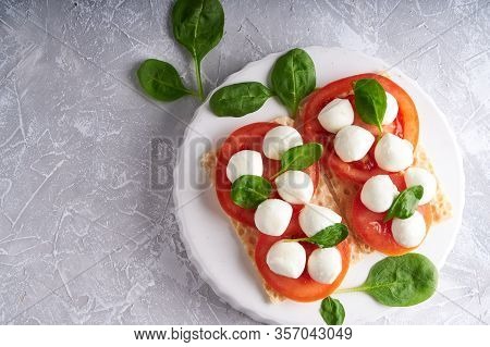 Toasts With Mozzarella, Tomatoes And Spinach In A White Plate