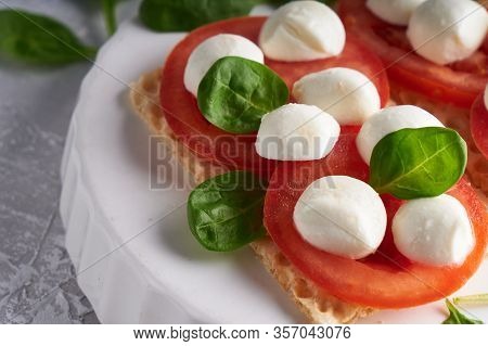 Toasts With Mozzarella, Tomatoes And Spinach In A White Plate Close Up