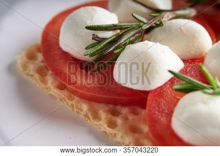 Toasts With Mozzarella, Tomatoes And Rosemary In A White Plate