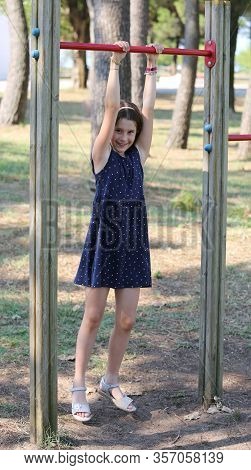 Pretty Girl Does Gymnastics On The Playground With Blue Dress In Summer