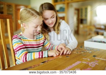 Cute Young Girls Playing Puzzles At Home. Children Connecting Jigsaw Puzzle Pieces In A Living Room