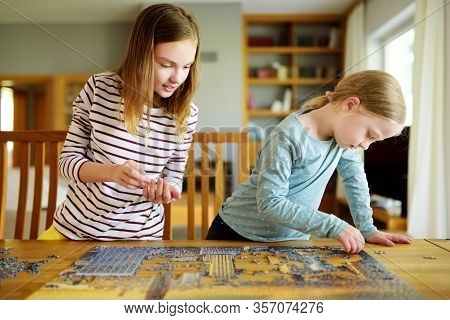 Cute Young Girls Playing Puzzles At Home. Children Connecting Jigsaw Puzzle Pieces In A Living Room