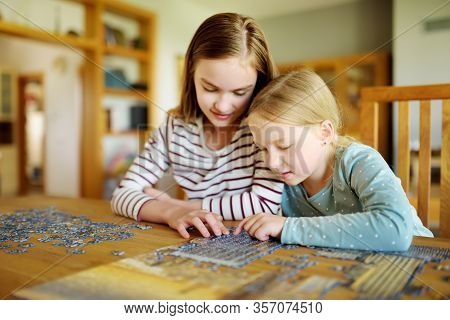 Cute Young Girls Playing Puzzles At Home. Children Connecting Jigsaw Puzzle Pieces In A Living Room