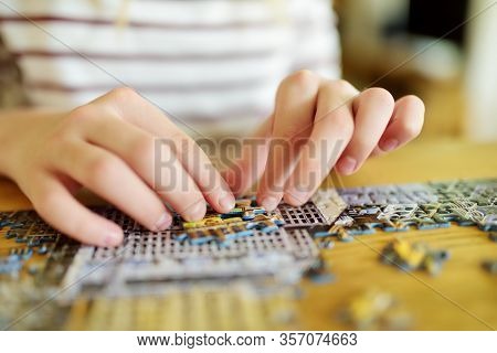 Close-up On Child's Hands Playing Puzzles At Home. Child Connecting Jigsaw Puzzle Pieces In A Living