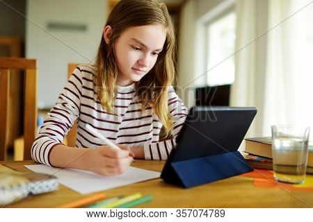 Smart Preteen Schoolgirl Doing Her Homework With Digital Tablet At Home. Education And Distance Lear