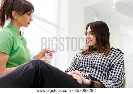 Dentist Doctor Shows The Patient A Jaw Model And Talks About The Upcoming Treatment.