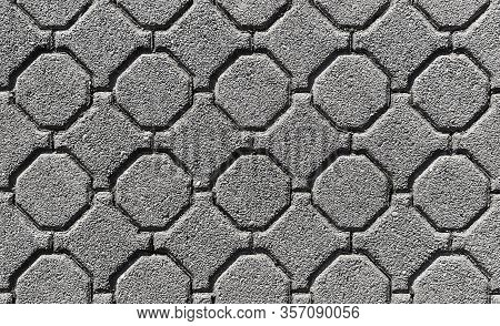 A Closeup Surface Of Grey Old Octagonal Almost Circular Paving Slabs, Uneven Worn Surface With Sunke
