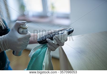 Woman Disinfects The Phone With A Spray Disinfectant Liquid.