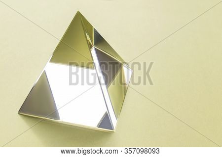 Clean And Transparent Glass Pyramid On A Yellow Background. Science, The Study Of Light Refraction. 