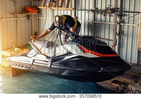 Senior Man Launching Or Lifting Modern Fast Jetski Hanged On Strpas With Wire Hoist Rail Crane For D