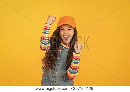 Happy Winner. Happy Little Girl Making Winning Gesture On Yellow Background. Cheerful Small Child Ha