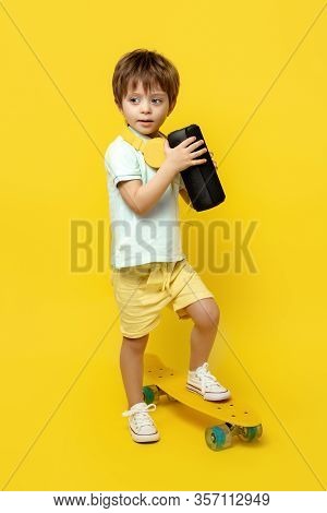 Full Lengh Photo Of Cute Kid Listening Music On Portable Black Wireless Speaker Over Yellow Backgrou