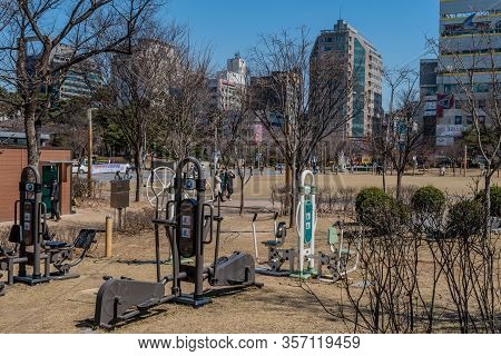Daejeon, South Korea; March 16, 2020: People Walking In City Park In Dunsan With Adult Exercise Equi