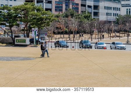 Daejeon, South Korea; March 16, 2020: Two Unidentified Young Women Walking Through Open Field In Cit