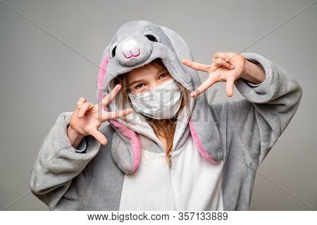 Teen Girl In Kigurumi Rabbit In A Medical Mask At Home In Quarantine. Close Up Hands Near The Face.