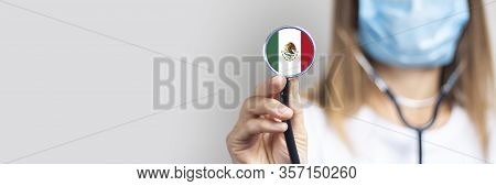 Female Doctor In A Medical Mask Holds A Stethoscope On A Light Background. Added Flag Of Mexico. Con