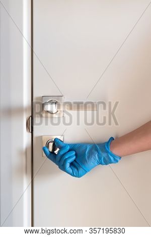 A Hand In A Latex Blue Glove Locks The Door. Quarantine. The Concept Of Self-isolation During A Pand