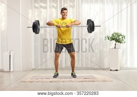 Full length portrait of a man lifting weigths at home