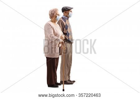 Full length profile shot of a senior couple with walking cane wearing medical face masks isolated on white background