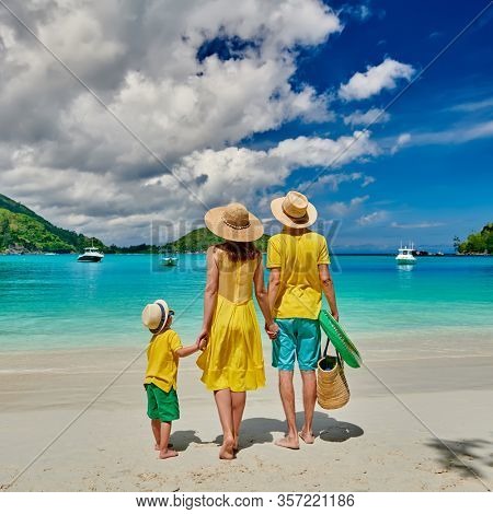 Family on beach, young couple in yellow with three year old boy. Summer vacation at Seychelles. Port Launay, Mahe. 