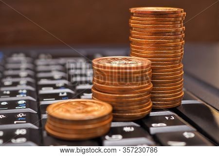 Piles Of Japanese Ten Yen Coins Stand On The Black Keyboard Of A Desktop Or Laptop. Behind Them Is A