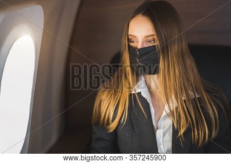 A Beautiful Young Blonde Woman In A Stylish Business Suit Sits On A Private Plane In A Black Medical