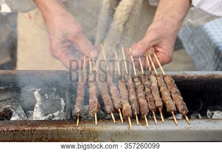 Hands Of Cook With Mutton Skewers Called Arrosticini In Italian At The Restaurant